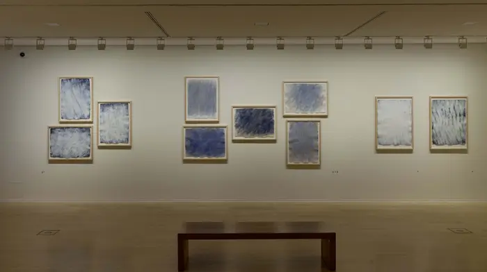 Blick auf Bank vor einer Wand mit gerahmten Grafiken