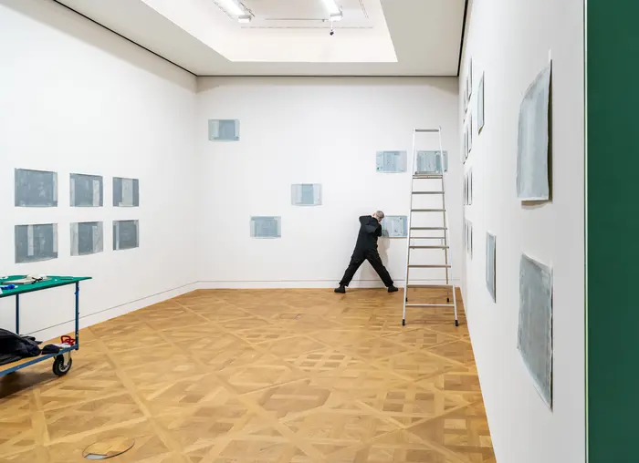 Aufbauarbeiten in einem hellen Ausstellungsraum mit Holzboden.