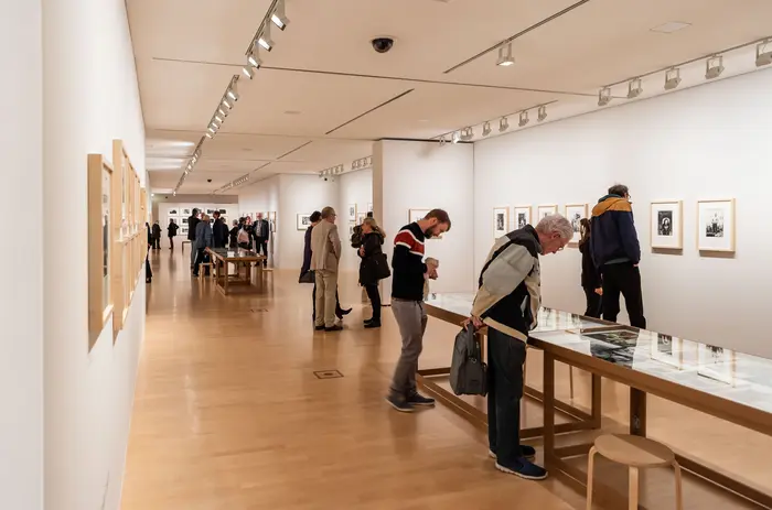 Menschen betrachten Kunstwerke in einem Ausstellungsraum.