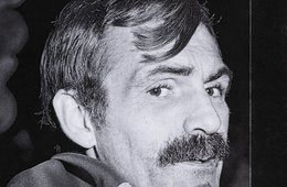 Die Schwarz-Weiß-Fotografie eines Mannes, der eine Flagge um die Schultern trägt.