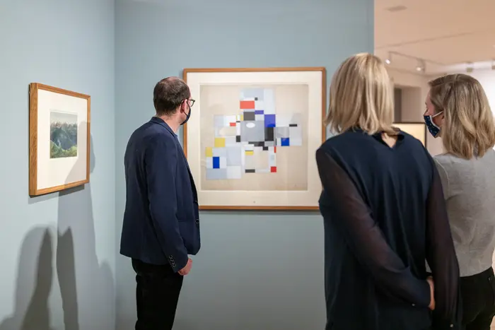 Personen betrachten ein Kunstwerk in einem Ausstellungsraum.