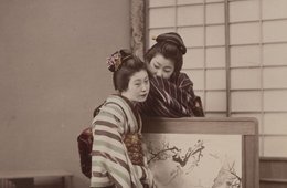 Unbekannter Fotograf, „Whispering“ (Zwei japanische Frauen an einem Stellschirm), 1870-1900 Frau flüstert anderer Frau ins Ohr, beide im Kimono, kleine Stellwand zwischen ihnen