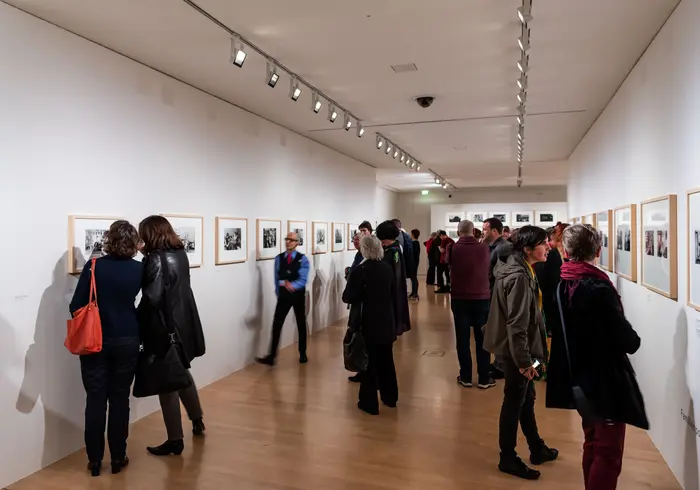 Menschen betrachten Kunstwerke in einem Ausstellungsraum.