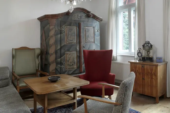 Raum mit großem Schrank, Tisch, Sesseln, Sofa, Kommode, Kronleuchter