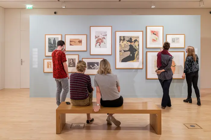 Personen betrachten Kunstwerke in einem Ausstellungsraum.