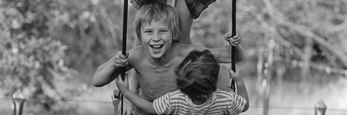 Schwarz-Weiß-Fotografie von drei Kindern auf einer Schaukel