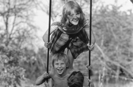 Schwarz-Weiß-Fotografie von drei Kindern auf einer Schaukel