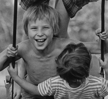 Schwarz-Weiß-Fotografie von drei Kindern auf einer Schaukel
