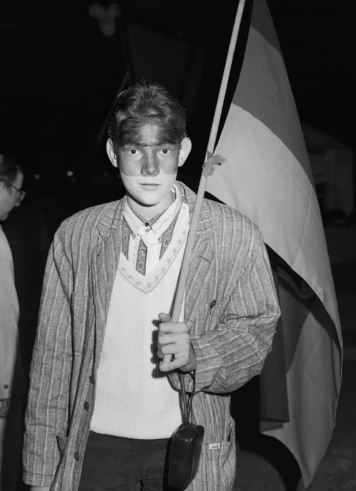 Die Schwarz-Weiß-Fotografie eines Mannes mit Deutschlandflagge und bemaltem Gesicht.