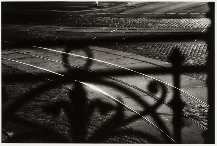 Schwarz-Weiß-Fotografie einer Straße mit Schienen und Kopfsteinpflaster.