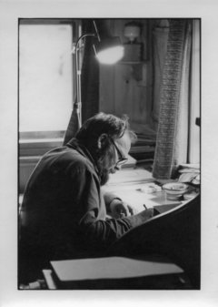 Schwarz-Weiß-Fotografie eines schreibenden Mannes am Schreibtisch