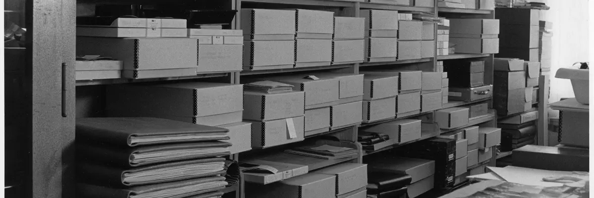 Schwarz-Weiß-Fotografie eines Regals mit Boxen und Mappen.