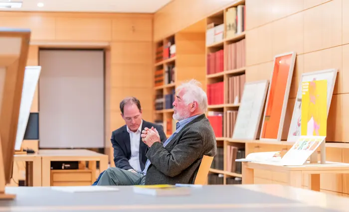 Zwei Männer sitzen in einem Ausstellungsraum.