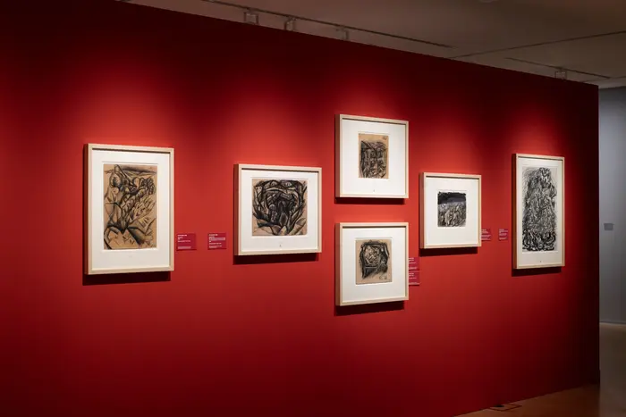 Gerahmte Zeichnungen an einer roten Wand.