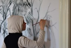 Eine Person malt etwas an eine Wand