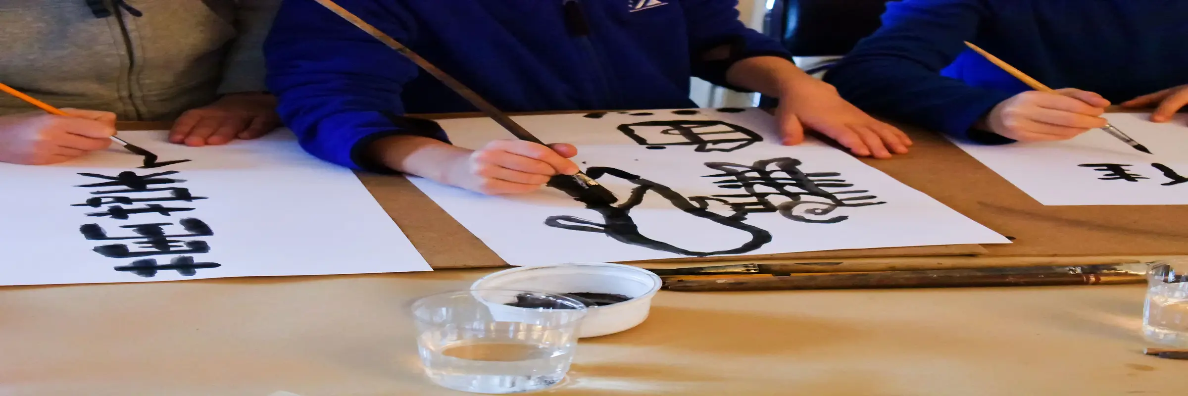 Drei Hände malen Hieroglyphen auf japanischem Papier
