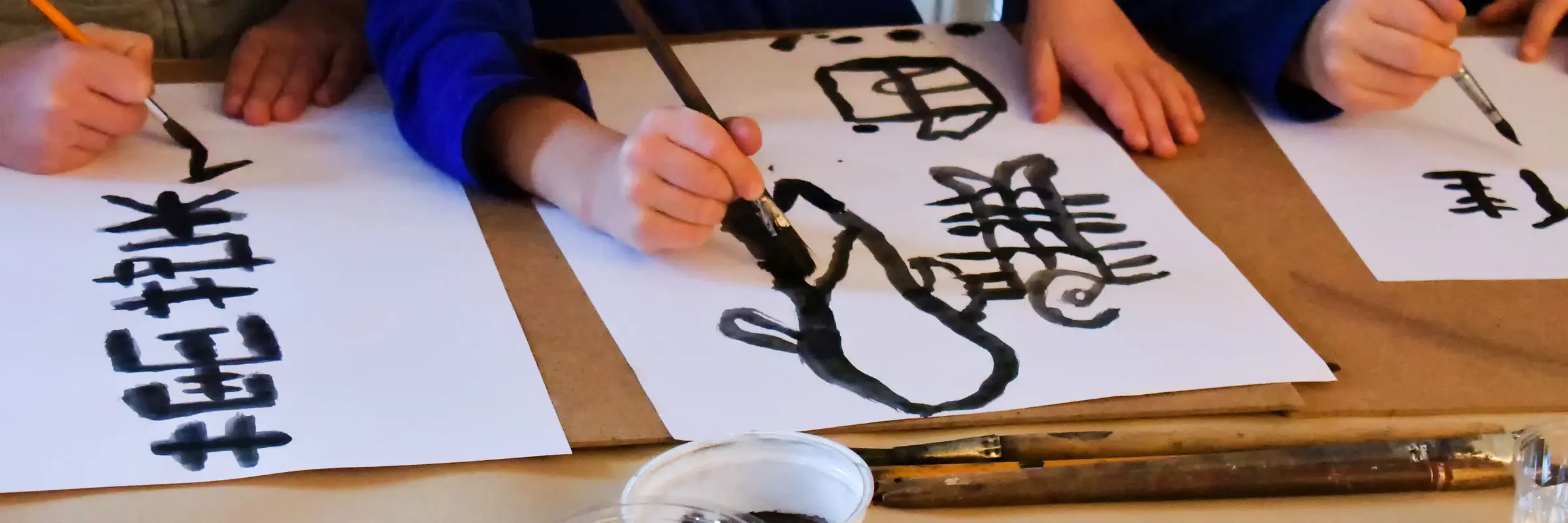 Drei Hände malen Hieroglyphen auf japanischem Papier