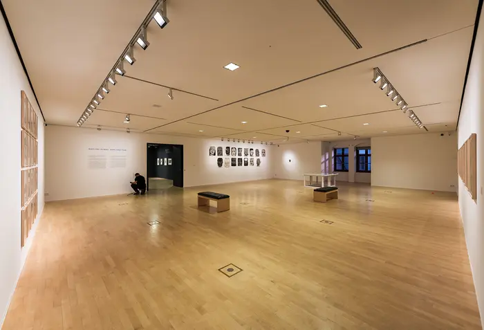 Ein großer Ausstellungsraum mit weisen Wänden und hölzernem Boden