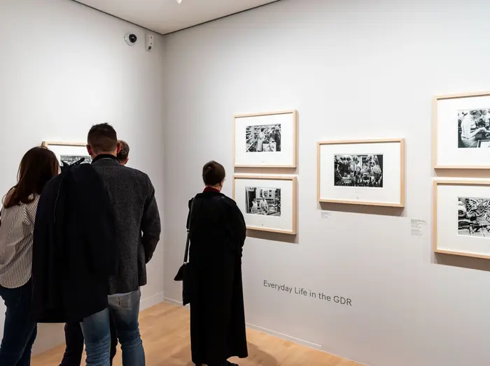 Menschen betrachten Kunstwerke in einem Ausstellungsraum.