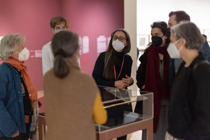 Eine Gruppe Menschen umringt ein Kunstwerk in einem Schaukasten.