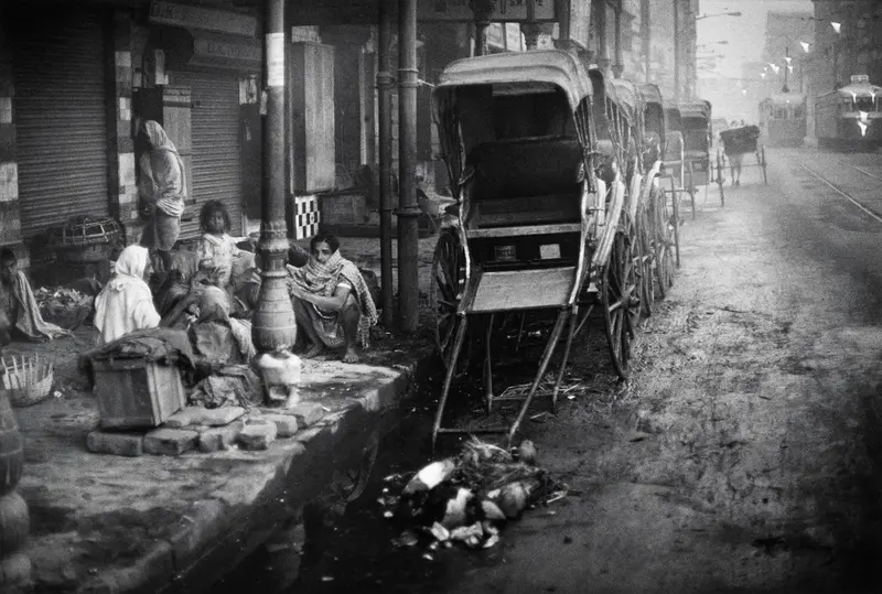 schwarz weiß Fotografie mit einer Rikscha und menschen, die auf der Straße sitzen