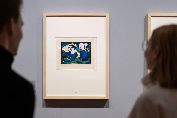 Zwei Menschen betrachten das gerahmte Bild eines weißen Pferdes.