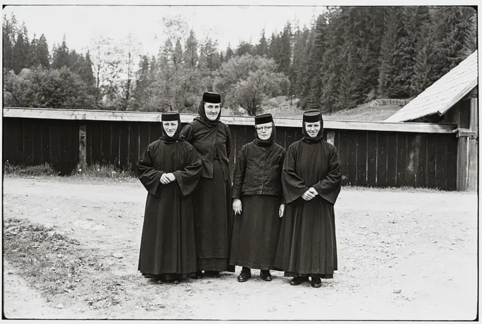 Schwarz-Weiß-Fotografie von vier Frauen in dunklen Gewändern und Hüten.