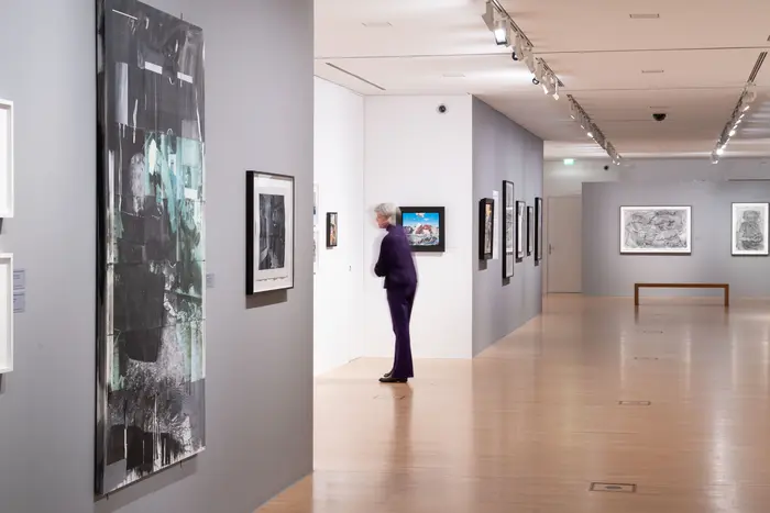 Raumansicht mit einer Person, die sich Kunstwerke anschaut