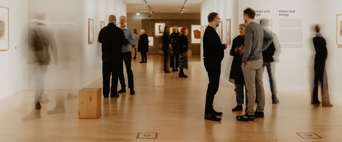 Ausstellungsansicht "Ich bin ein Sender... Zeichnungen von Joseph Beuys" Zwei Personen betrachten gerahmte Zeichnungen in Ausstellungsraum