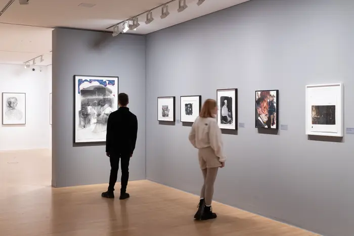 Raumansicht mit zwei Personen, die sich Kunstwerke anschauen