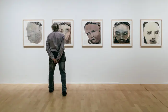 Mann beim Betrachten der Serie Jesus Grizzly von Marlene Dumas.