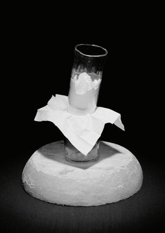 Pulver in einem schmalen Glasgefäß, darunter zweites Glasgefäß, zwischen Gefäßen Papier