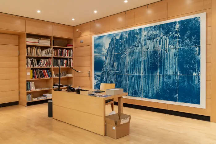 Ein blaues Kunstwerk an der Wand eines holzvertäfelten Raumes mit einem Schreibtisch in der Mitte.