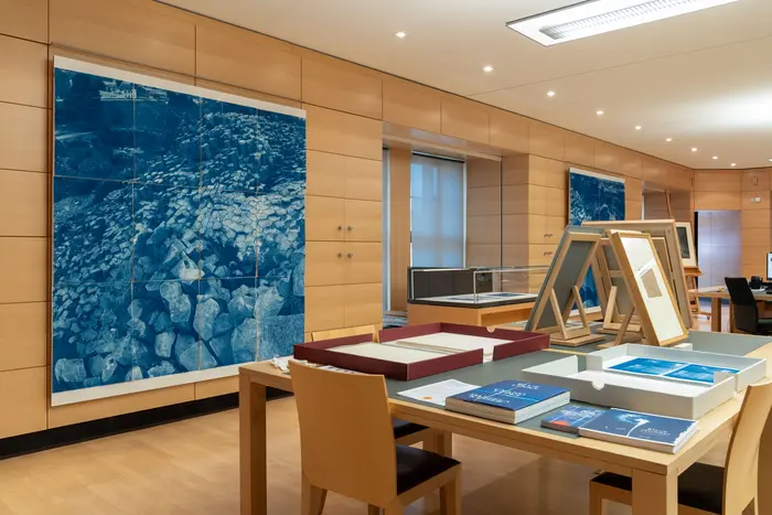 Arbeitstische in einem Raum mit großen, blauen Kunstwerken an den Wänden.