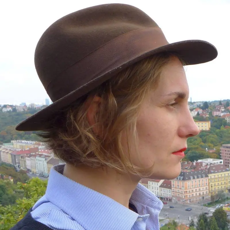 Ein Foto zeigt das Profilbild einer Frau mit kurzen hellen Haaren und braunem Hut