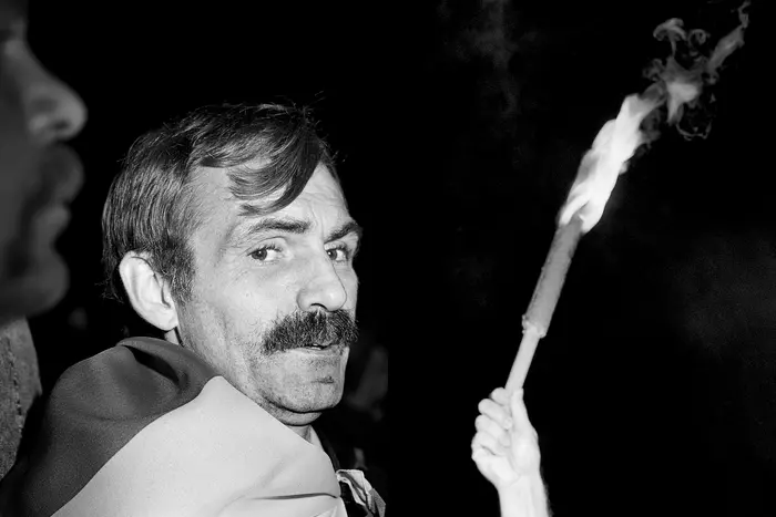 Die Schwarz-Weiß-Fotografie eines Mannes, der eine Flagge um die Schultern trägt.