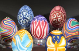 Neun bunt bemalte Ostereier vor einem dunklen Hintergrund.