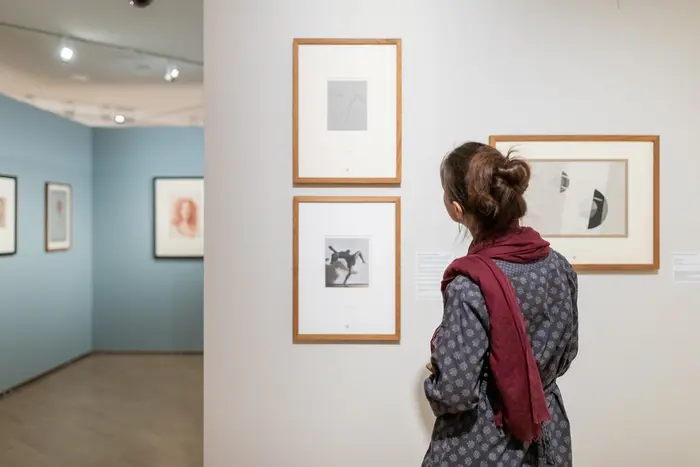 Eine Besucherin betrachtet Kunstwerke in einem hellen Ausstellungsraum.